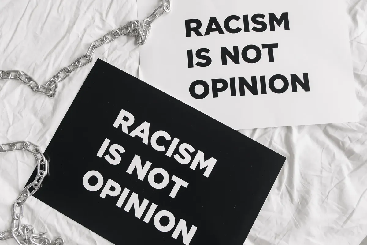 Black and white protest signs reading 'Racism is Not Opinion' on white fabric.