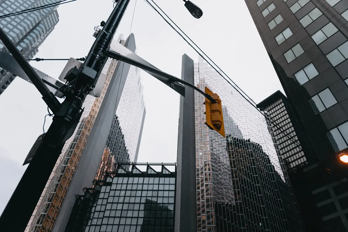 Modern urban skyline featuring towering skyscrapers and a traffic light in downtown Toronto.