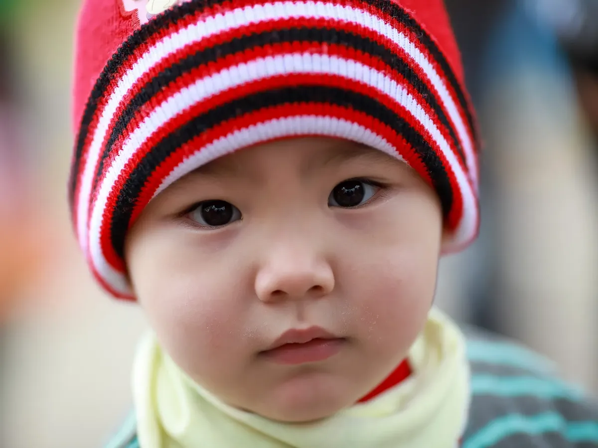 Close-up of a child's face wearing a red and white hat, capturing innocence and cultural essence in Lào Cai, Vietnam.