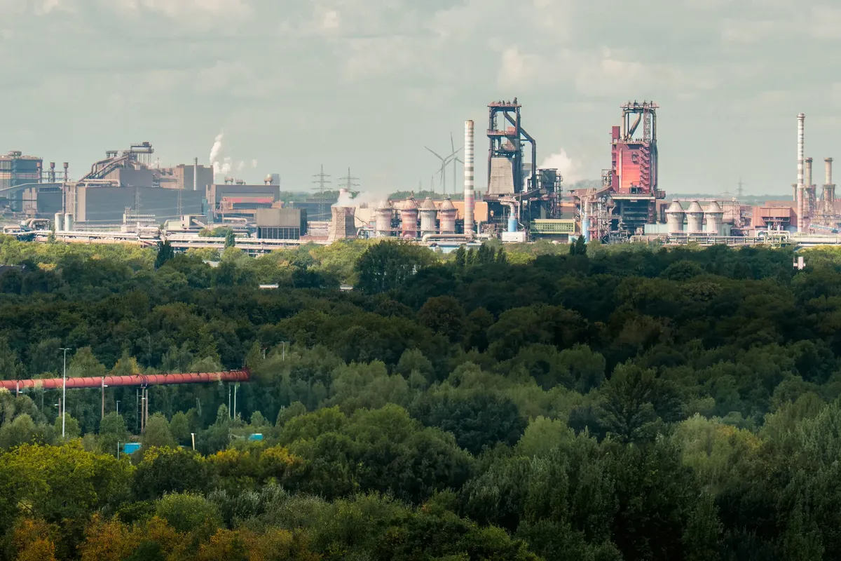 View of heavy industry and lush forest in Duisburg, Germany.