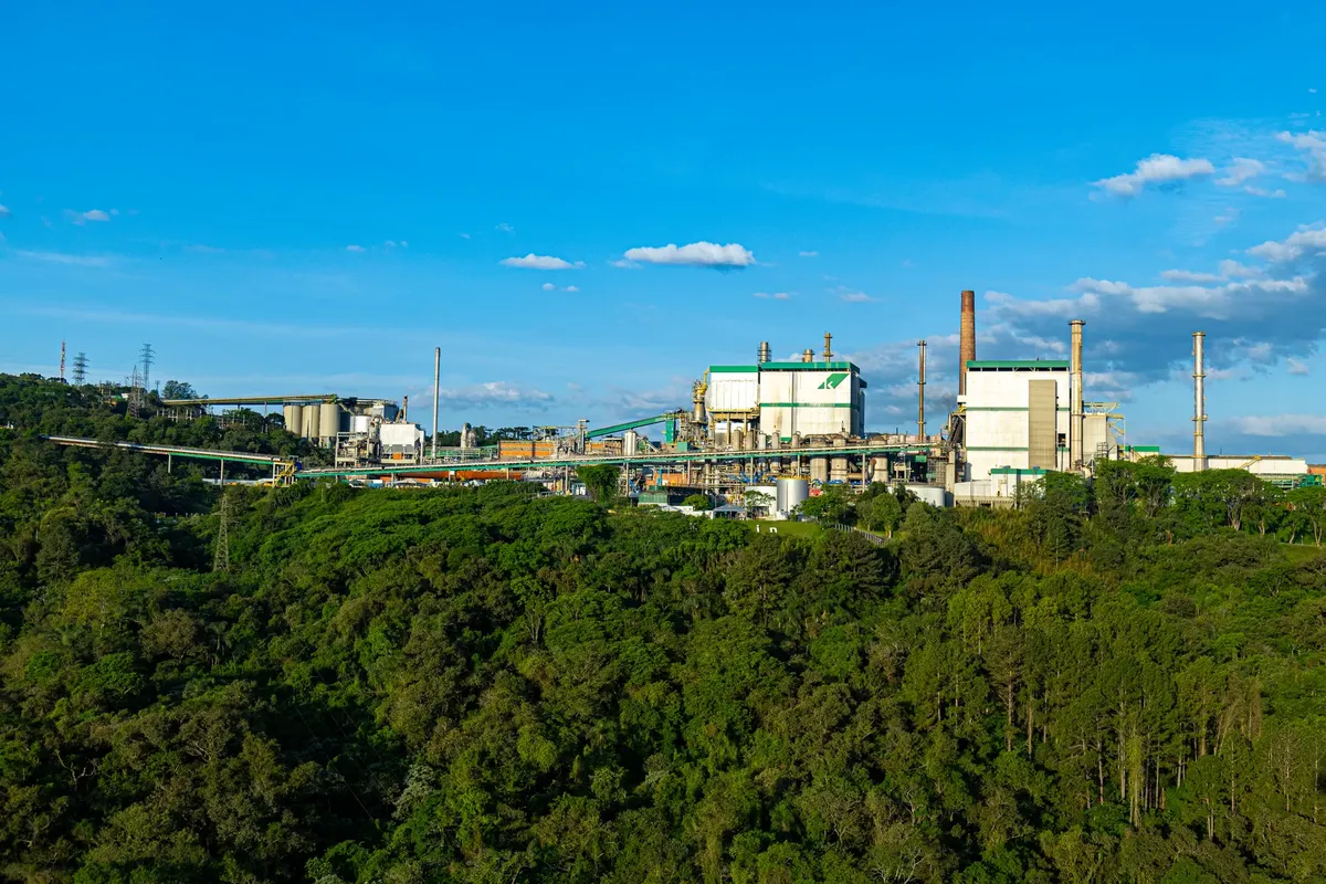 Wide shot of an industrial plant surrounded by dense forest in Telêmaco Borba, Brazil.