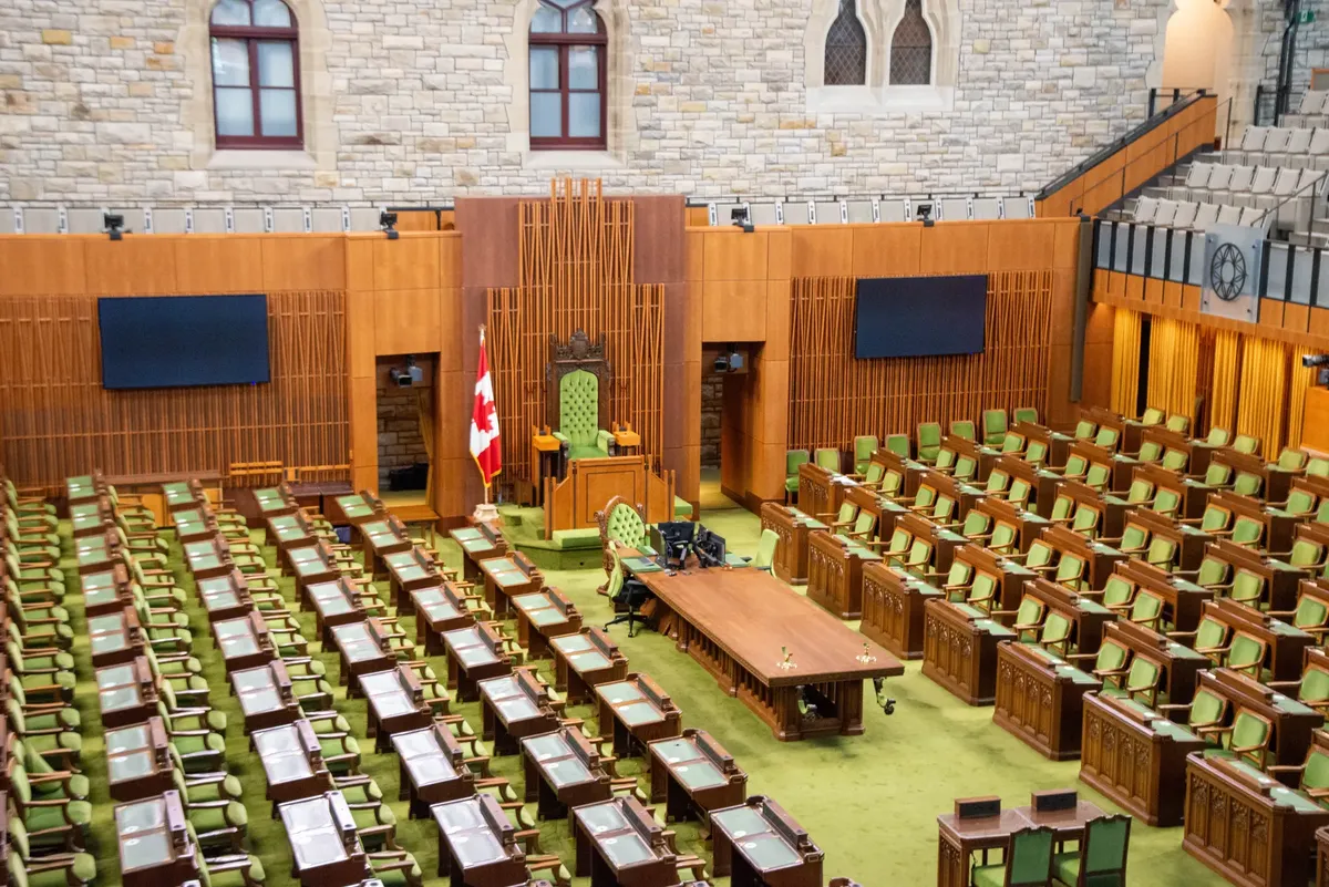 Interior view of the Canadian House of Commons with green seating and wooden decor.